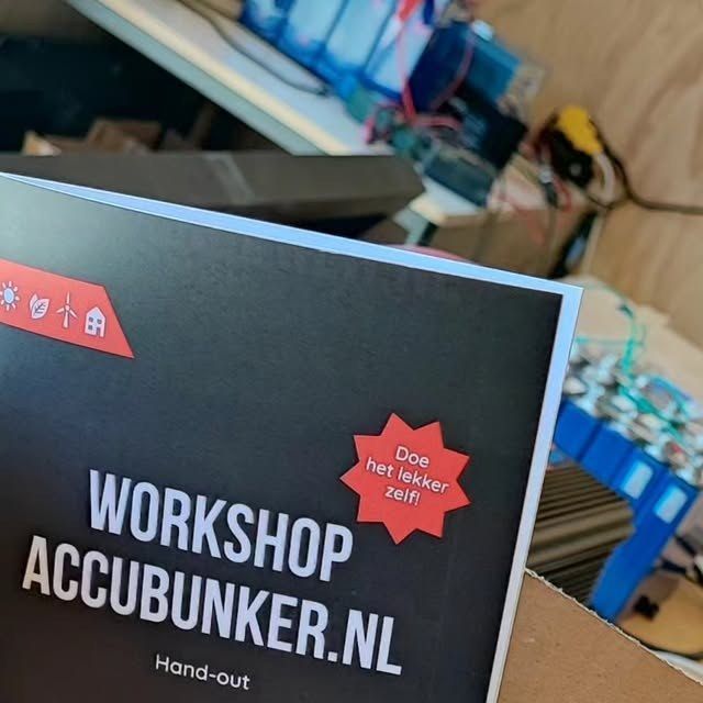 Een AccuBunker-workshophand-out met batterijcellen en workshopmateriaal op de achtergrond.